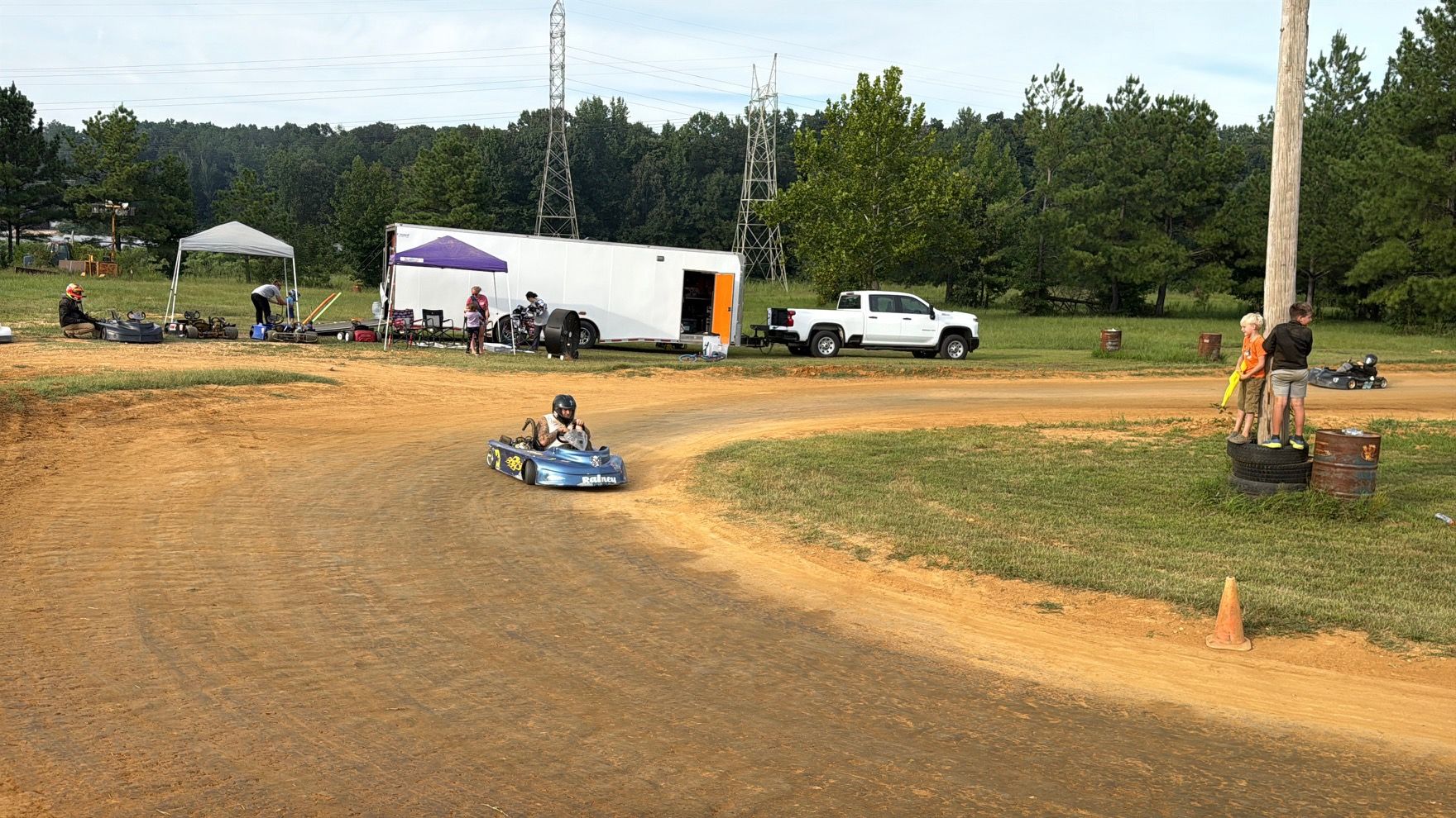 Ronnie's blue 3 kart rolling through the corner at Camden Speedway past the haulers